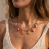 Junge Frau it dunklen Haaren und sommerlicher Kleidung trägt eine Kette mit Charms im Maritimen Look