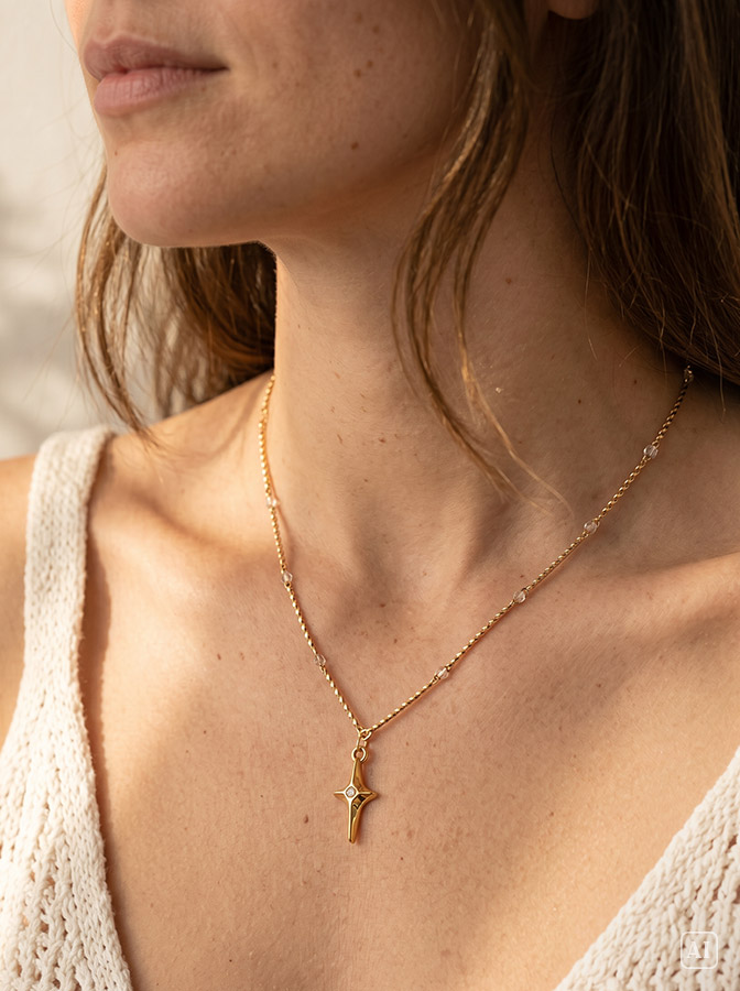 Junge Frau mit dunklen Haaren trägt eine filigrane goldene Kette mit Stern Anhänger