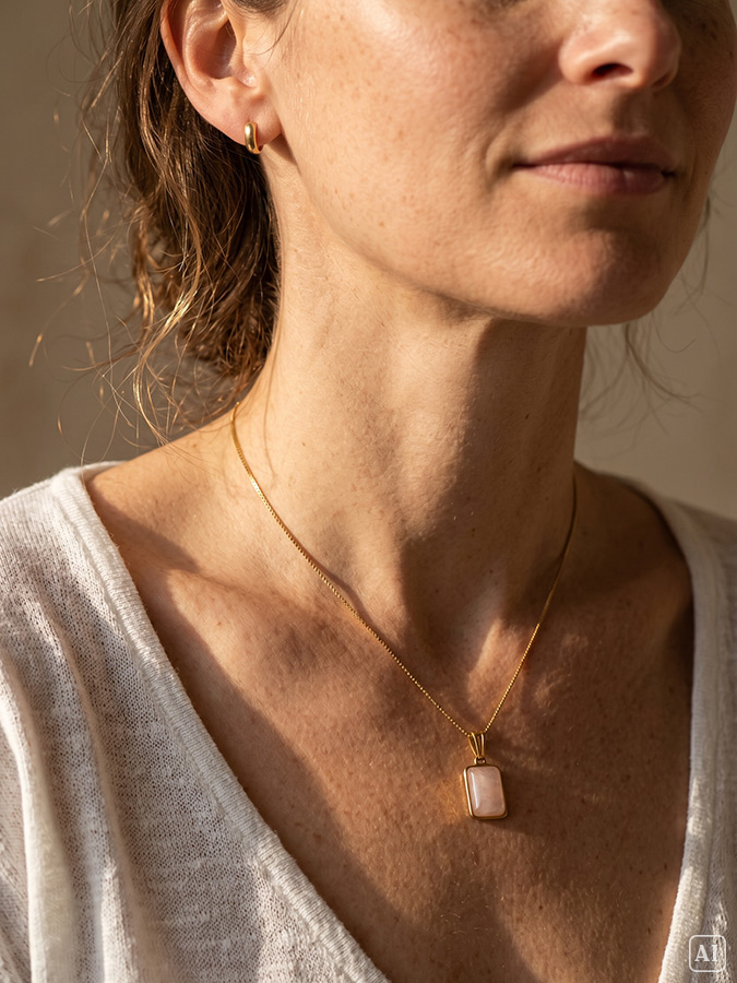 Styling Tipp: Junge Frau mit dunklen hochgesteckten Haaren trägt eine filigrane Gold Kette mit Stein Anhänger in Rosa