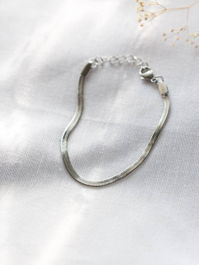 Flaches Schlangenarmband Silber auf hellem Stoff