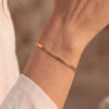 Flaches Schlangenarmband Gold, getragen am Handgelenk einer Frau