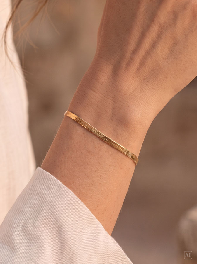 Flaches Schlangenarmband Gold, getragen am Handgelenk einer Frau