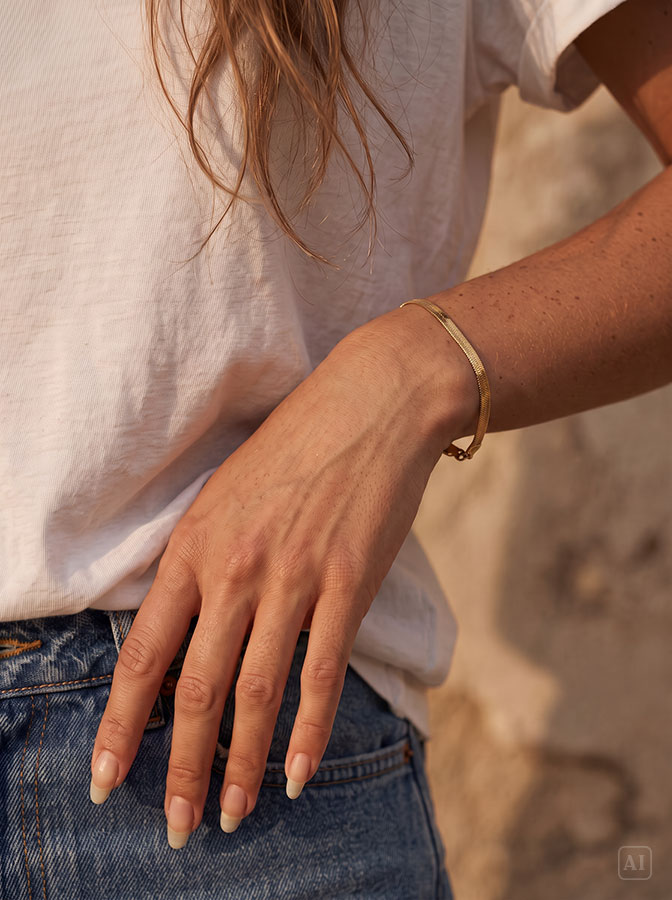 Flaches Schlangenarmband Gold, getragen am Handgelenk einer Frau