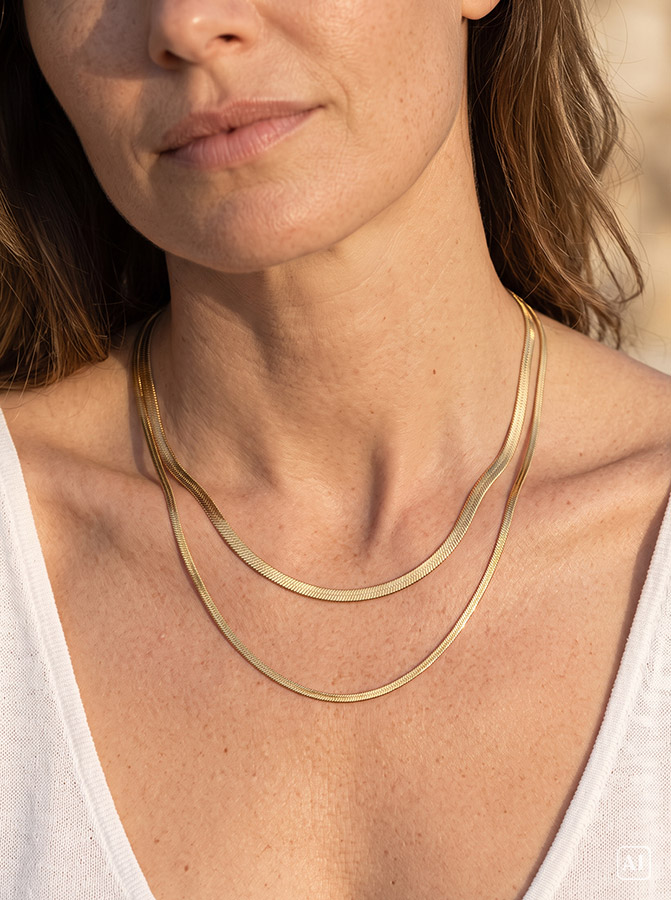 Junge Frau trägt eine flache Schlangenkette in Gold
